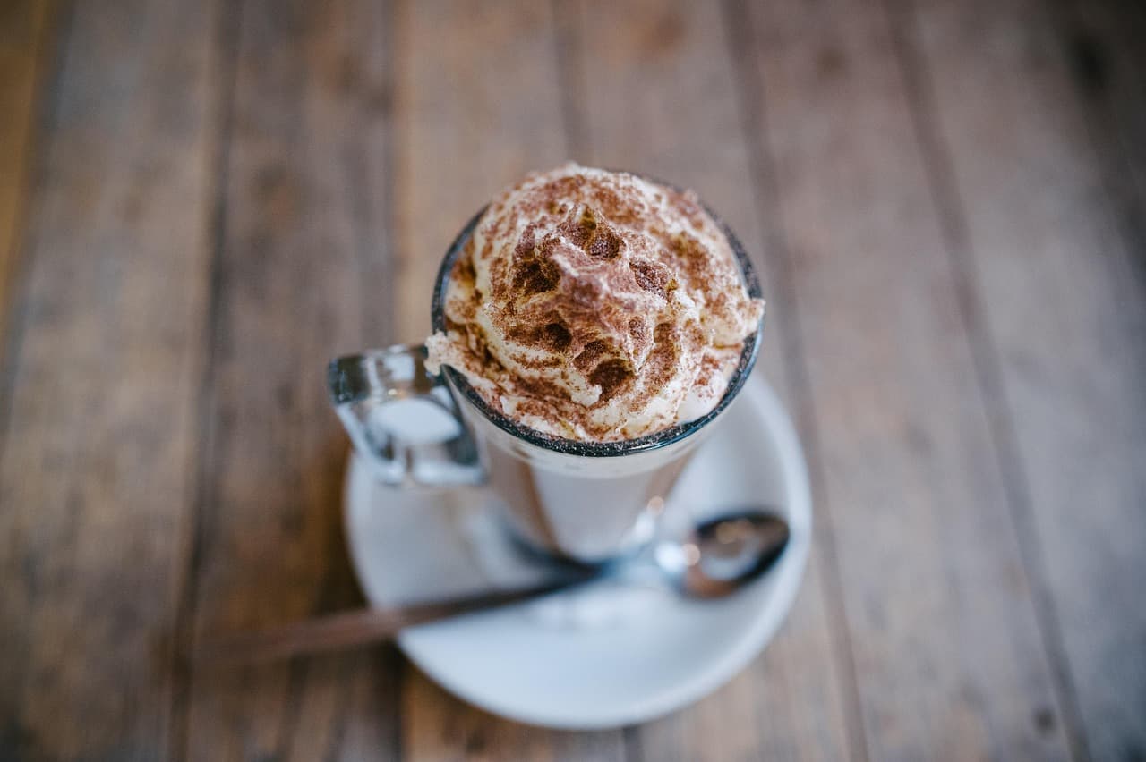 Hot chocolate topped with cream and cocoa on a wooden table
