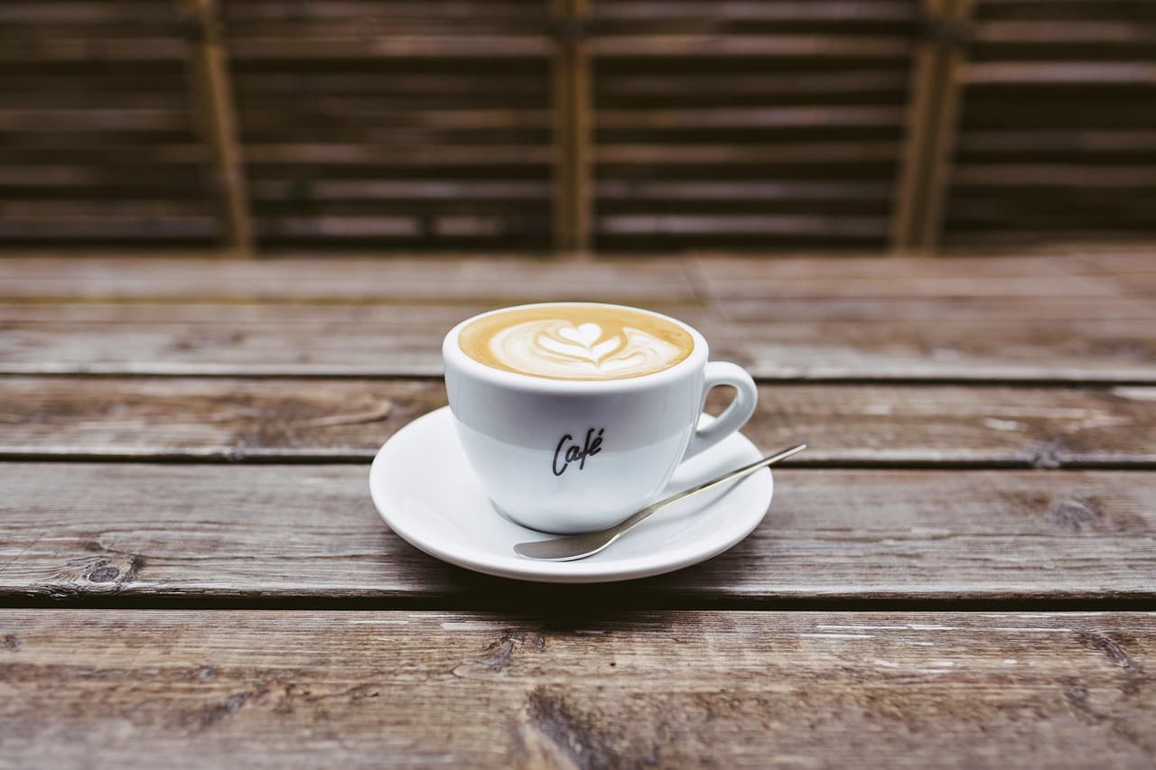 A cappuccino on a saucer on a weathered wooden table
