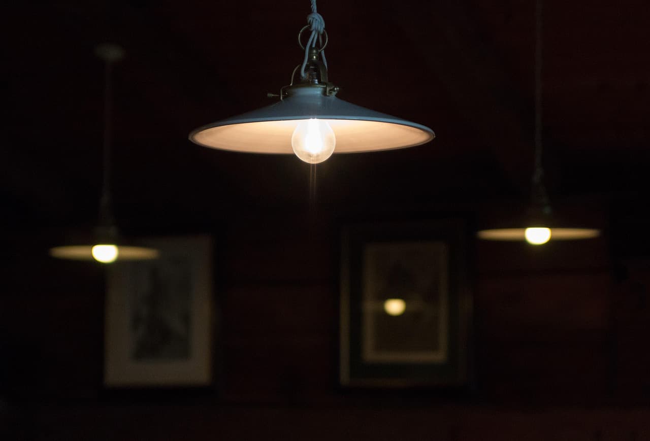 Pendant lamps glowing low over a dim, warm dining room