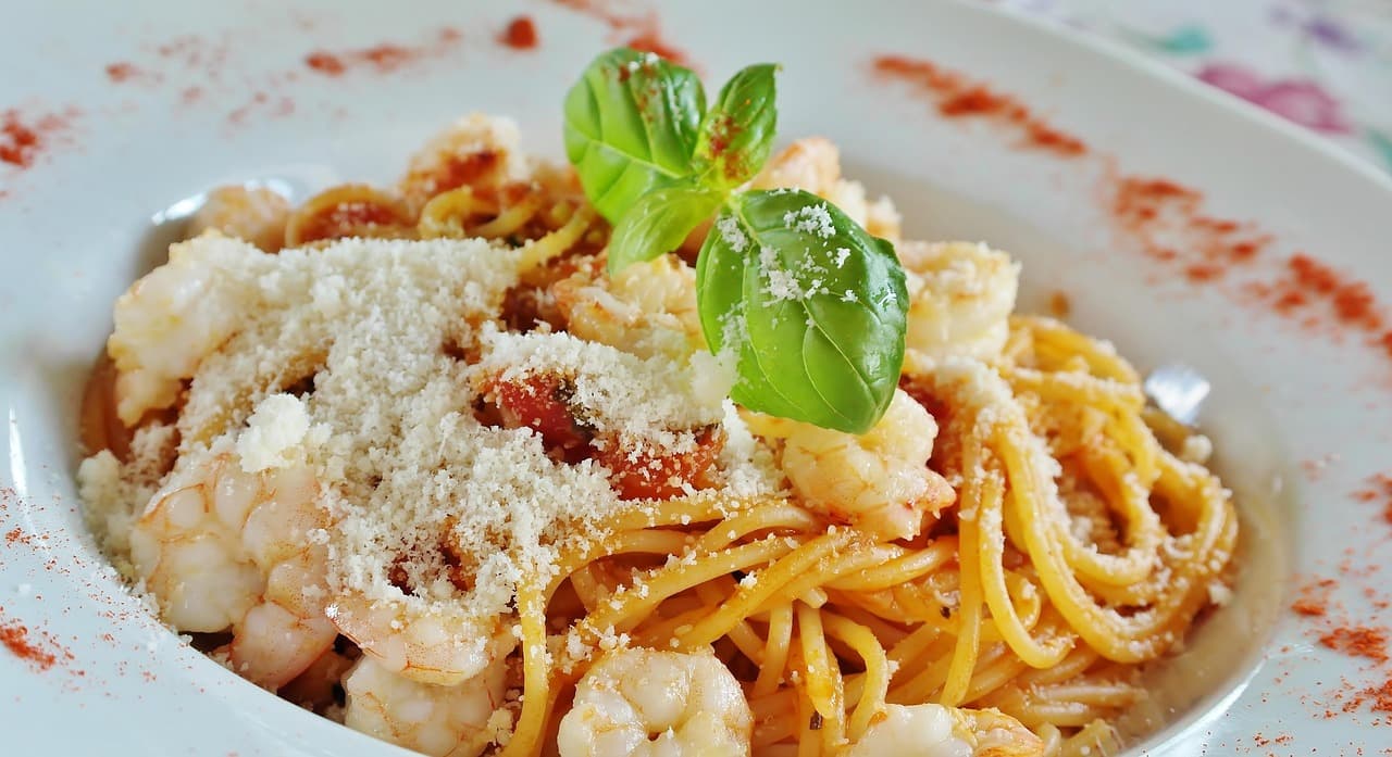 Spaghetti with prawns, tomato, parmesan and basil in a white bowl